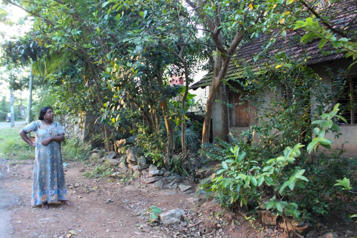 A woman beside her house in Vilappilsala. She lives across the street from the garbage facility. Most of her neighbors have fled their homes.